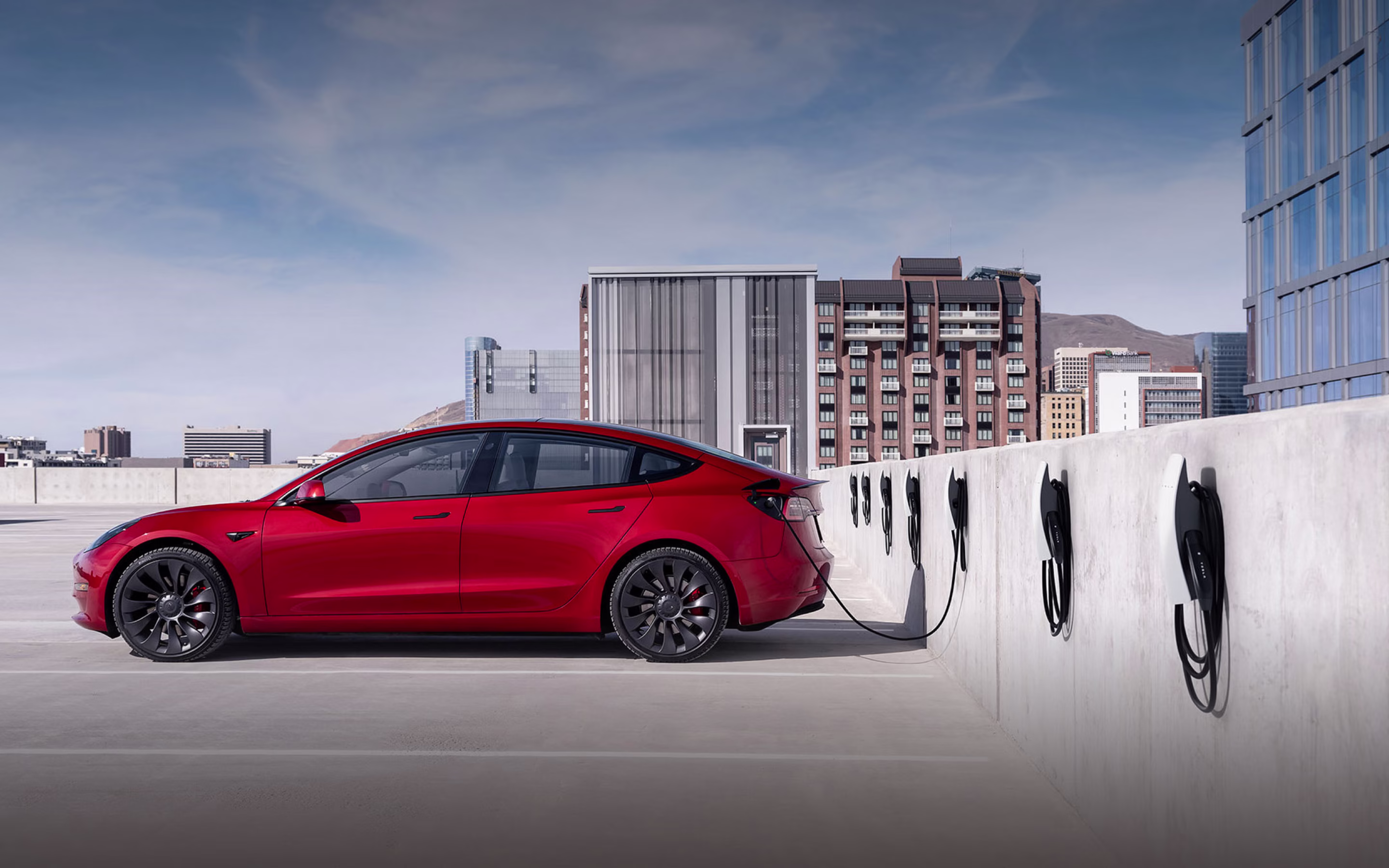 Şarj İş Ortakları — otoparkta Wall Connector sırası ve kırmızı Tesla